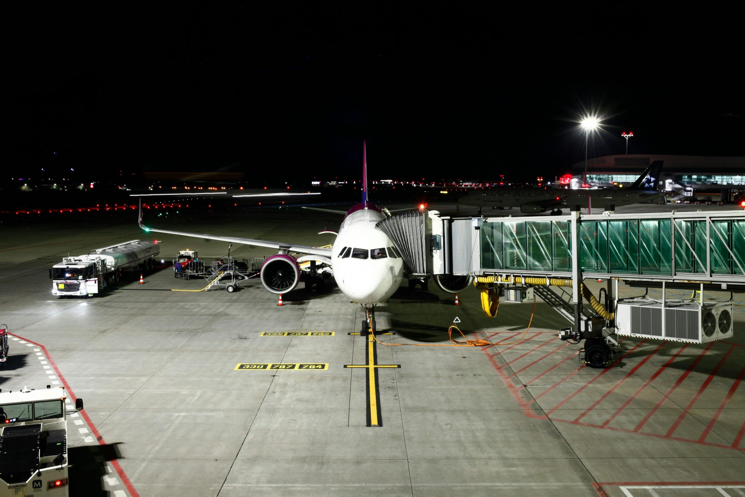 A large passenger airplane is docked at an airport terminal under night skies, ready for its next flight.